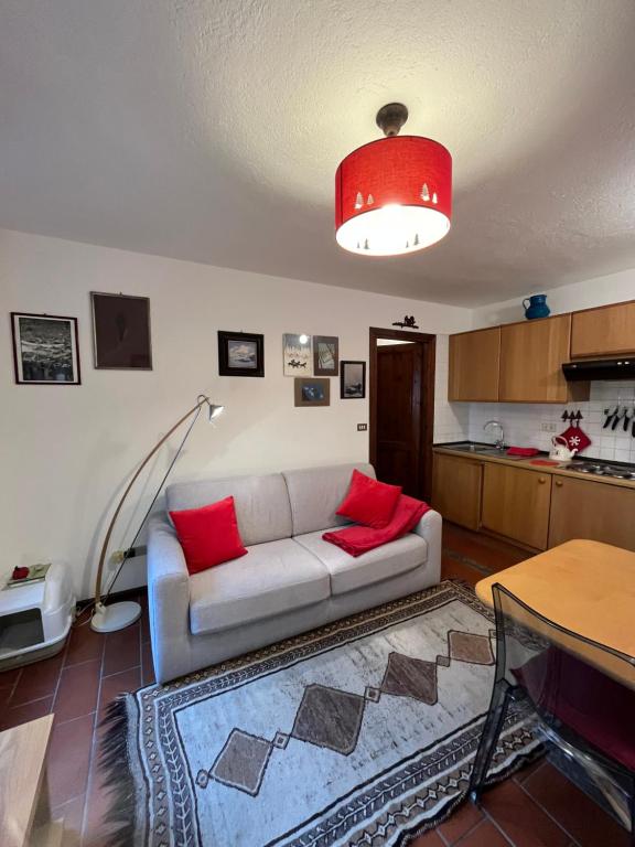 een woonkamer met een witte bank en rode kussens bij casa nel bosco cir vda 0192 in Courmayeur