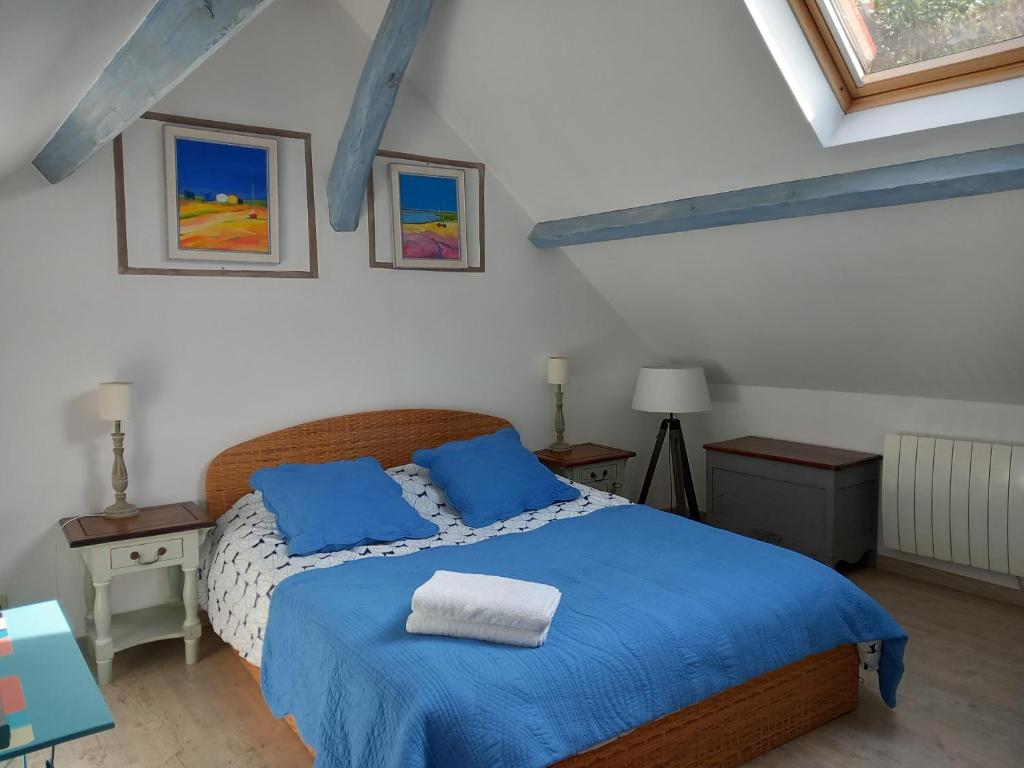 a bedroom with a blue bed with two blue pillows at La Bord de Mer (au Portail Bleu) in Châtres