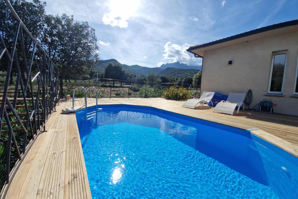 une piscine bleue avec une terrasse en bois à côté d'une maison dans l'établissement Domaine U Filanciu - Maison Chiara avec piscine - Centre Corse, à Moltifao