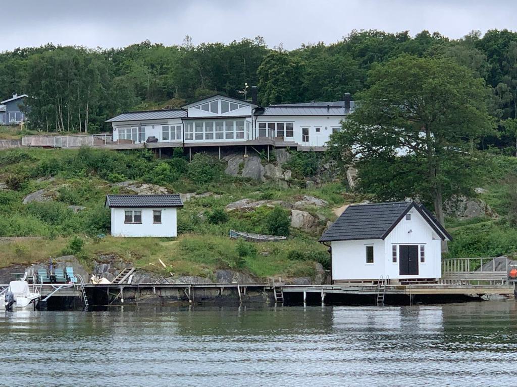 een paar witte huizen aan de kant van een waterlichaam bij Exclusive house with private boathouse in Nösund