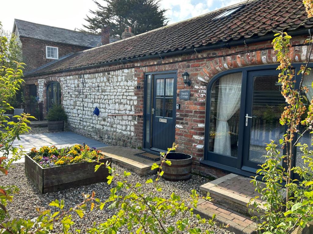 a brick house with a door and a garden at Sarah's Cottage in Bridlington