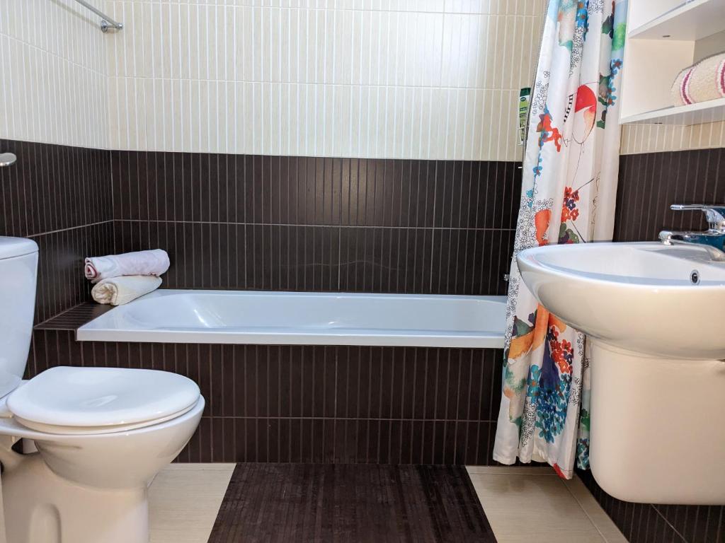 een badkamer met een bad, een toilet en een wastafel bij Cozy ground floor appartment with communal pool in Paralimni