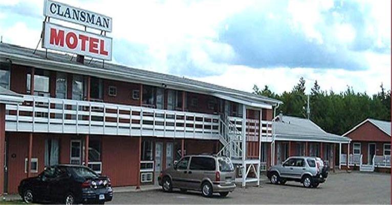 a motel with two cars parked in a parking lot at Clansman Motel in North Sydney