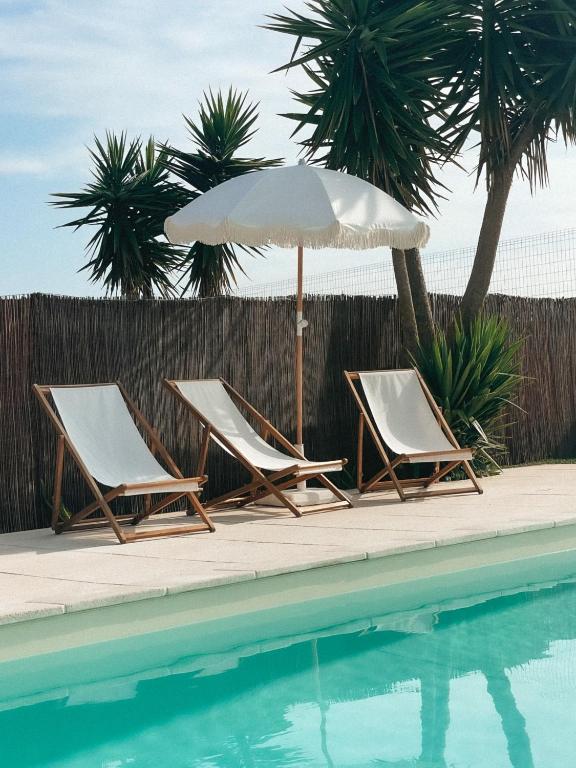 two lounge chairs and an umbrella next to a swimming pool at Quinta Amarela - B&B in Nazaré
