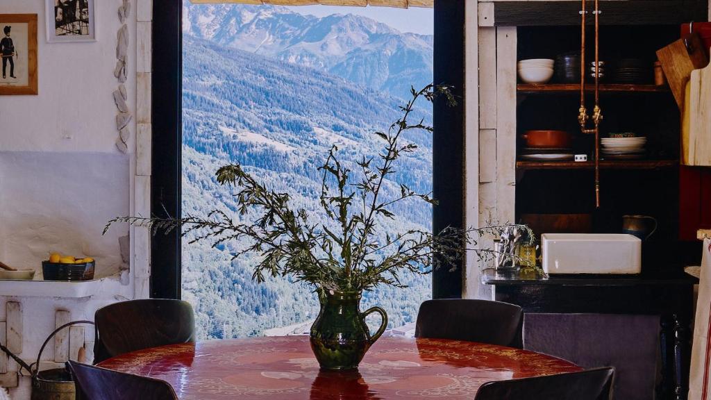 un vase avec des fleurs sur une table avec vue dans l'établissement Cozy Alpine Retreat in the mountain, à Bourg-Saint-Maurice