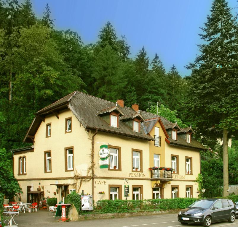 una grande casa con una macchina parcheggiata di fronte di Pension Waldheim a Friburgo in Brisgovia