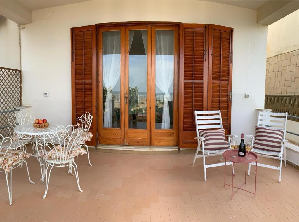 een patio met stoelen, een tafel en een houten deur bij Casa On The Beach in Alcamo