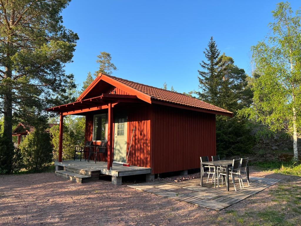 a small red cabin with a deck and chairs at Björkö Stugor 