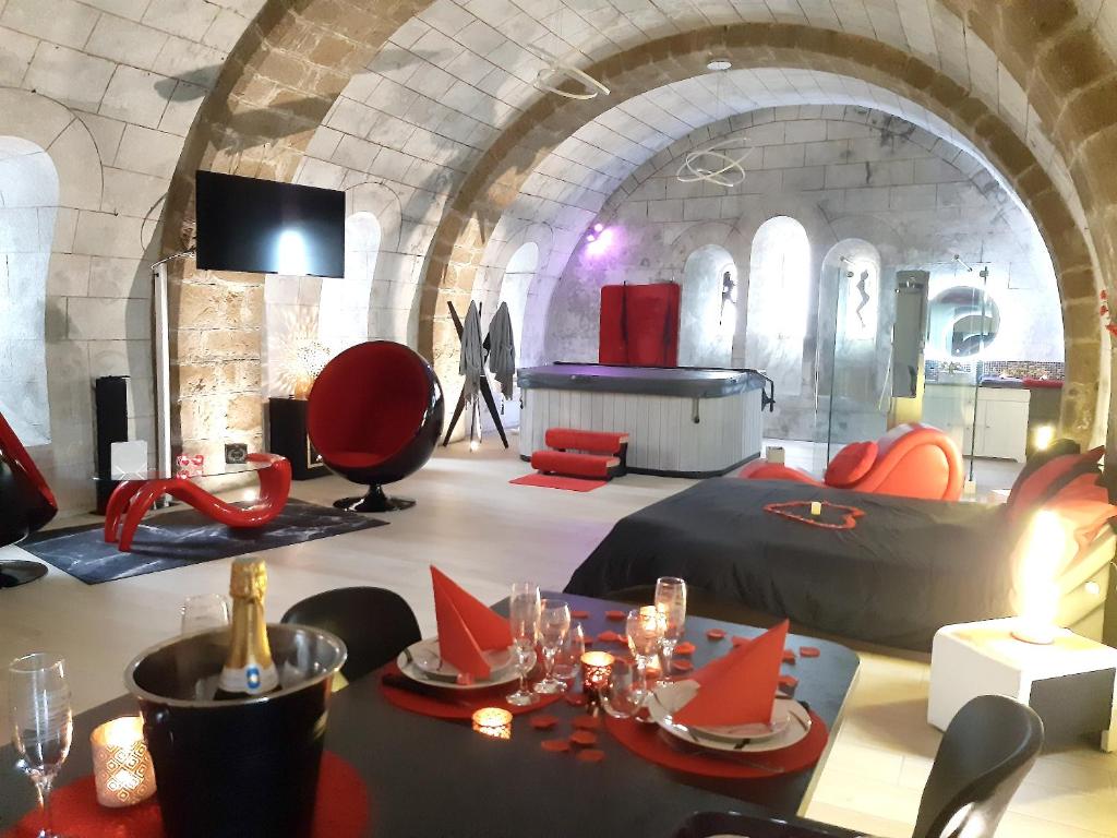 a room with a table with red chairs and a room with an arch at Studio avec jacuzzi terrasse amenagee et wifi a Ambrieres les Vallees in Ambrieres Les Vallees
