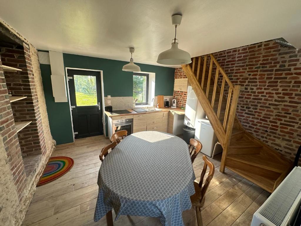eine Küche mit einem Tisch und eine Küche mit einer Treppe in der Unterkunft Gite confortable au milieu des prés - La ferme de Montigny in Neauphe-sur-Dives