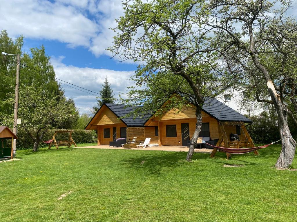 a log cabin with a hammock in the yard at Domki na lipowej in Pastwiska