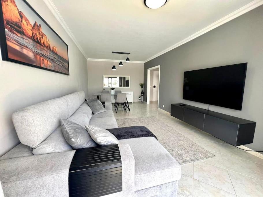 a living room with a couch and a flat screen tv at Luxury Modern Beach Apartment in Quarteira