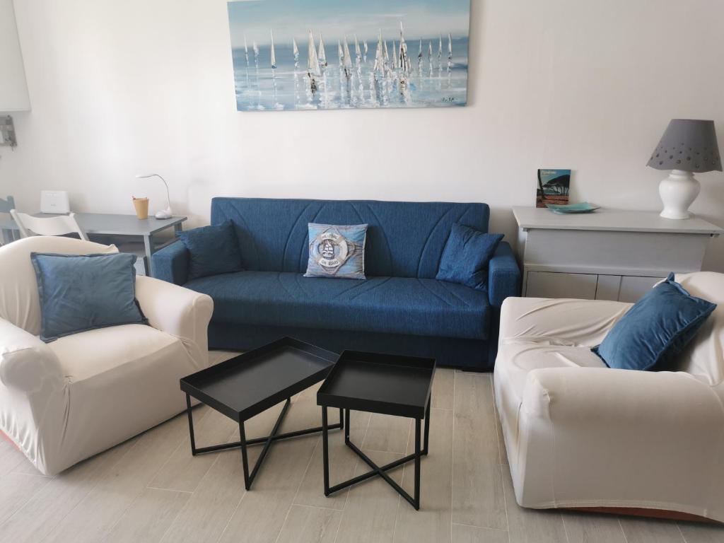 ein Wohnzimmer mit einem blauen Sofa und weißen Stühlen in der Unterkunft Casa al mare con giardino, 2 km spiaggia golfo di Baratti & parco archeologico in Baratti
