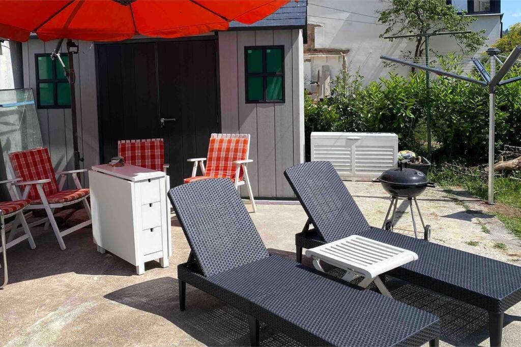 a patio with two chairs and an umbrella and a grill at Moderne EG 2-Zimmer Wohnung in Trier