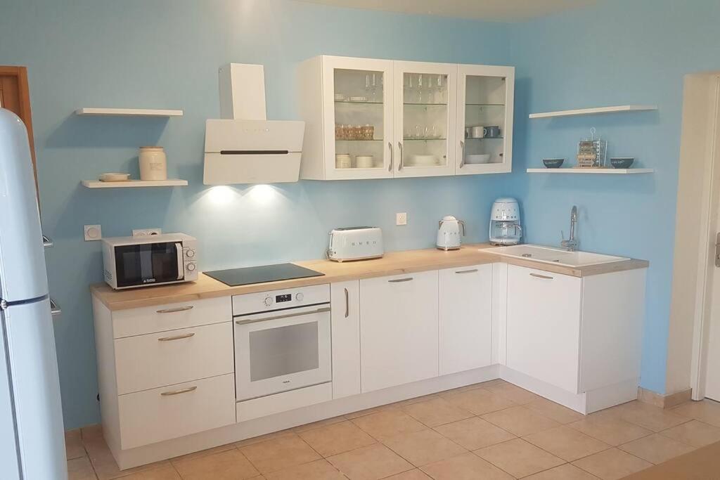 a kitchen with white cabinets and a sink and a microwave at La MAISON BLEUE, Smeg Bleu azur in Évian-les-Bains