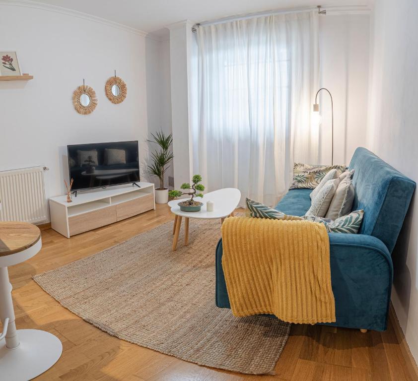 sala de estar con sofá azul y mesa en APARTAMENTO CARMELA en Santiago de Compostela