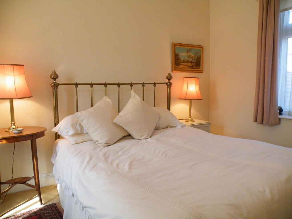 a bedroom with a white bed with two lamps at Broadlands Gate in Brockenhurst