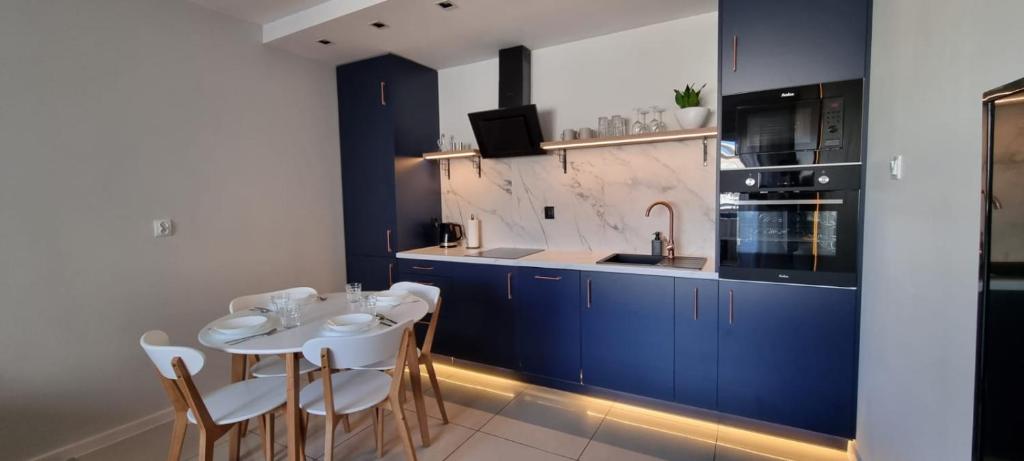 una cocina con armarios azules y una mesa y sillas blancas. en Apartament 51 en Toruń