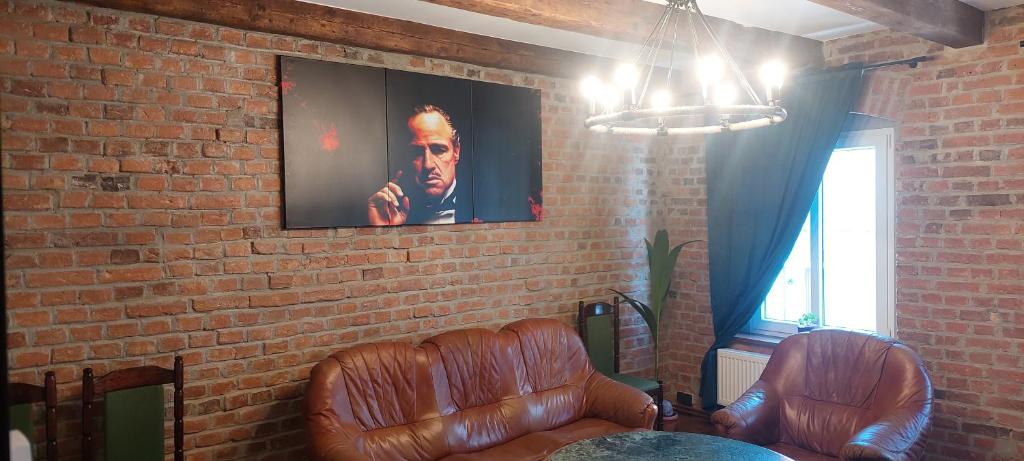 a room with two leather chairs and a brick wall at Apartament loftowy in Świdnica