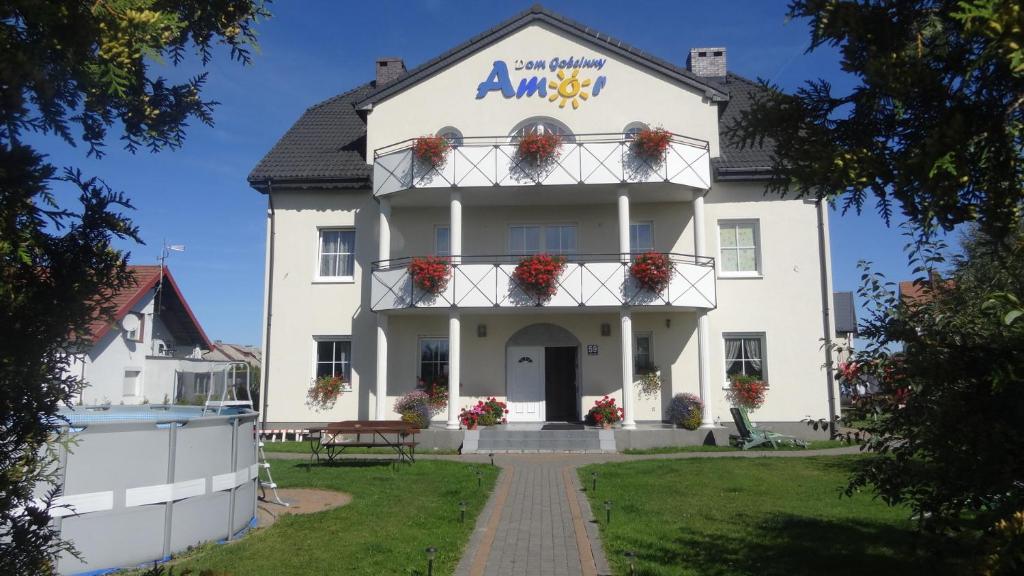 a white building with flowers on the balcony at Pensjonat Amor in Mielno