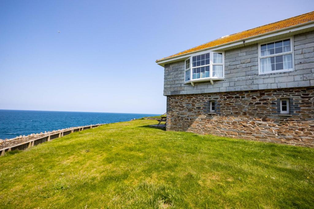 a house on a grassy hill next to the ocean at Gulland in Port Isaac