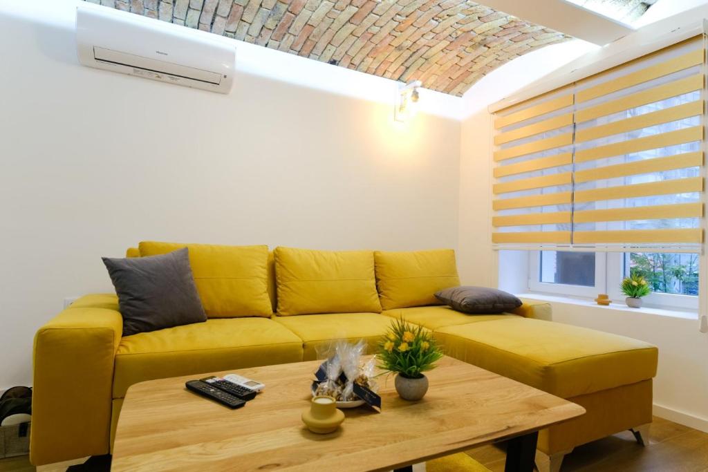 a living room with a yellow couch and a table at All seasons apartments Sarajevo with free parking in Sarajevo