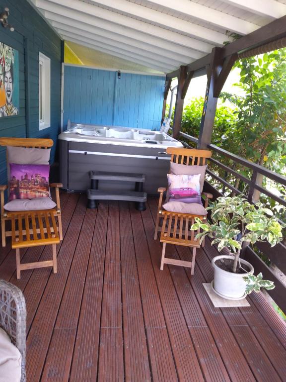 a screened porch with a hot tub on a deck at LES GÎTES DU DOMAINE DE PETITE-ANSE in Bouillante