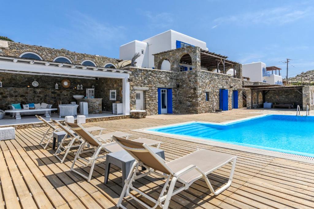 a villa with a swimming pool and chairs on a deck at Salty Blè in Agios Ioannis Mykonos
