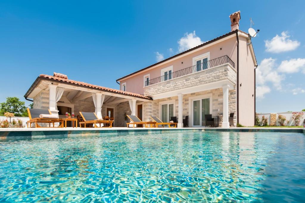 a villa with a swimming pool in front of a house at Villa Valentina in Žminj