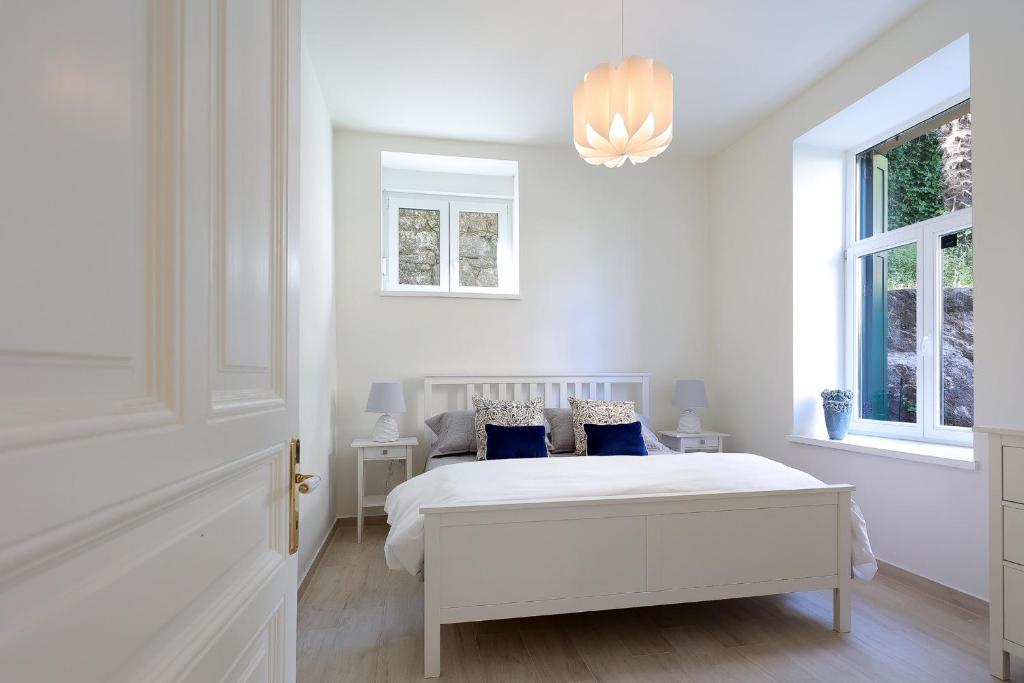 biała sypialnia z łóżkiem i 2 oknami w obiekcie Apartment with patio 50m from the beach and Lungomare w mieście Opatija