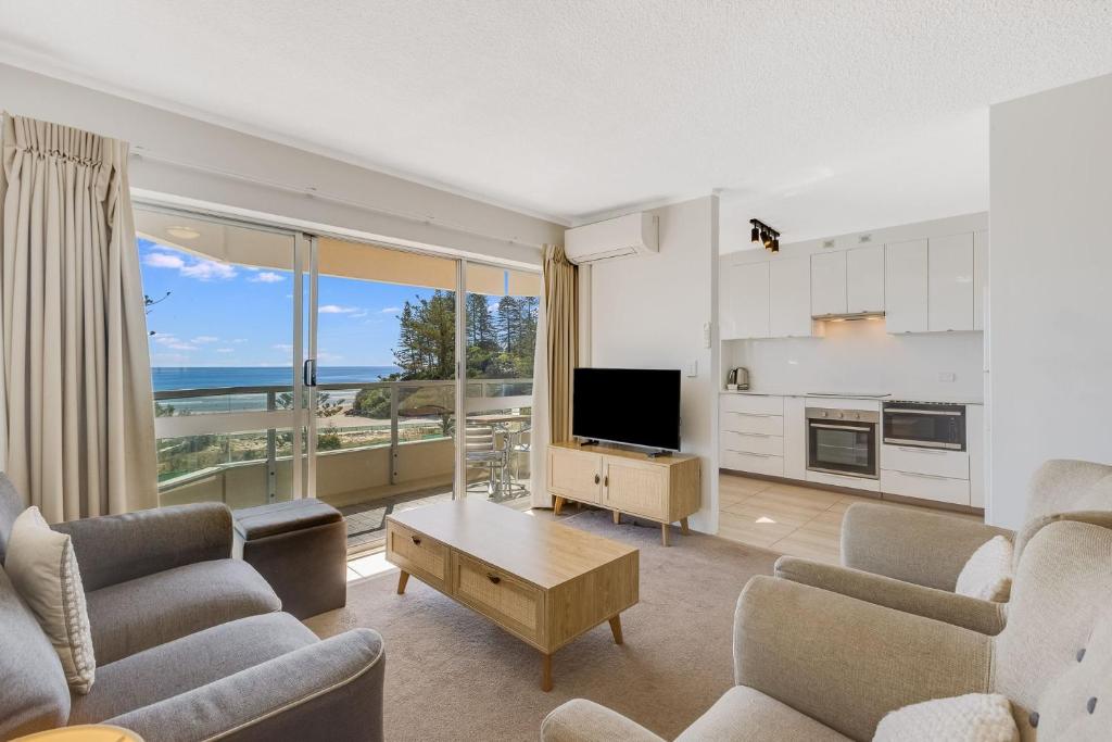 a living room with a couch and a tv and a kitchen at Kooringal Unit 16 in Gold Coast