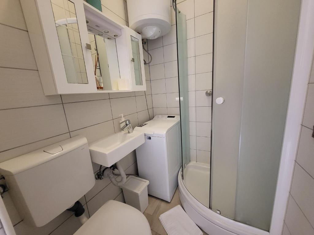 biała łazienka z toaletą i umywalką w obiekcie Apartment with patio 50m from the beach and Lungomare w mieście Opatija