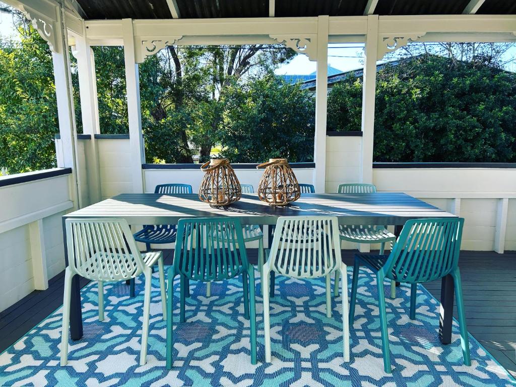 einen Tisch mit Stühlen und Vasen auf einer Veranda in der Unterkunft Gorgeous Arthouse Queenslander In Ipswich in Bundamba