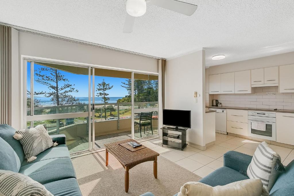 a living room with a blue couch and a kitchen at Kooringal Unit 10 in Gold Coast