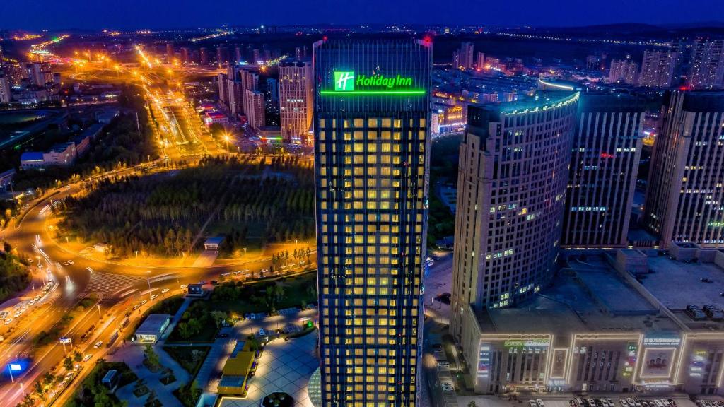 um edifício alto com um sinal verde em cima em Holiday Inn Changchun Oriental Plaza, an IHG Hotel em Changchun