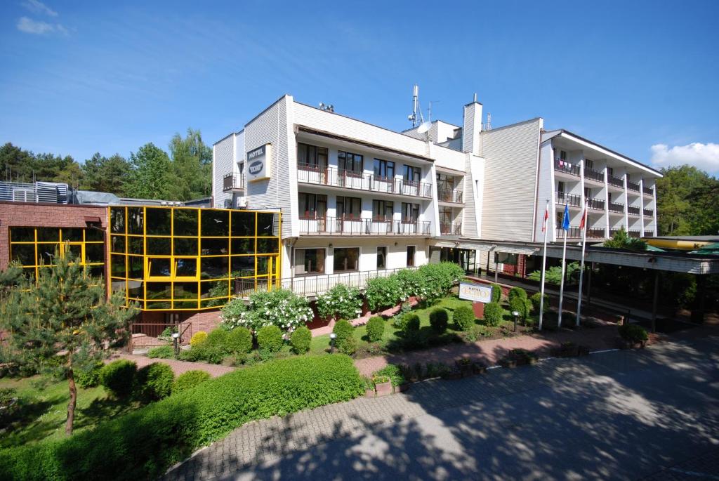 a large white building with a garden in front of it at Hotel Echo in Cedzyna