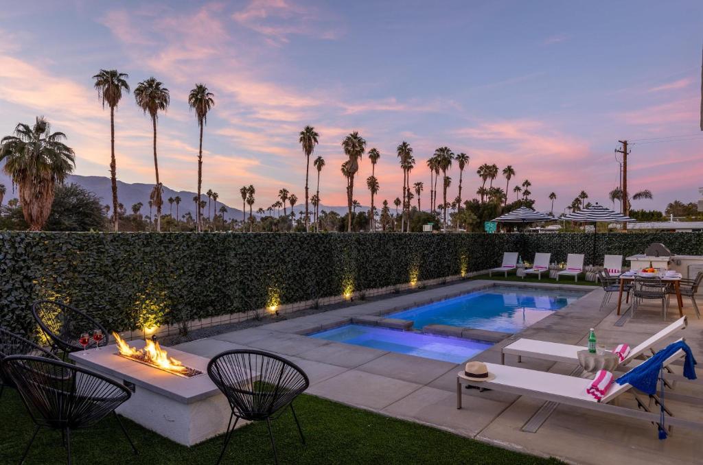 a backyard with a swimming pool and a patio with palm trees at Picture Perfect Retreat in Palm Springs