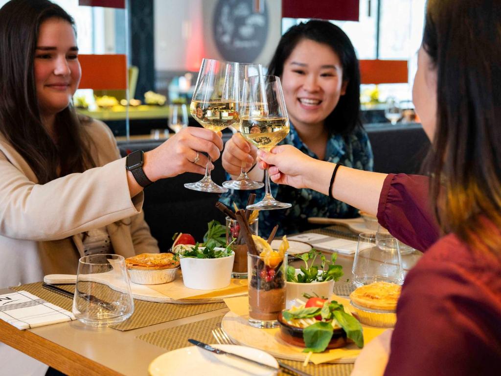 a group of people sitting around a table drinking wine at Novotel Amsterdam City in Amsterdam