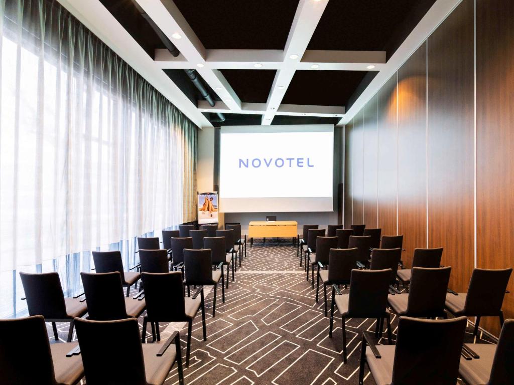 a conference room with chairs and a projection screen at Novotel Amsterdam City in Amsterdam