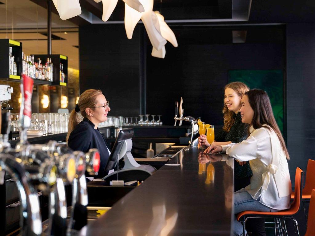 two women sitting at a bar in a restaurant at Novotel Amsterdam City in Amsterdam