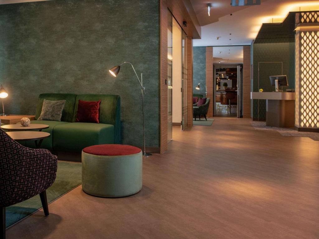 een woonkamer met een groene bank en een tafel bij Mercure Hotel Koeln Belfortstrasse in Keulen