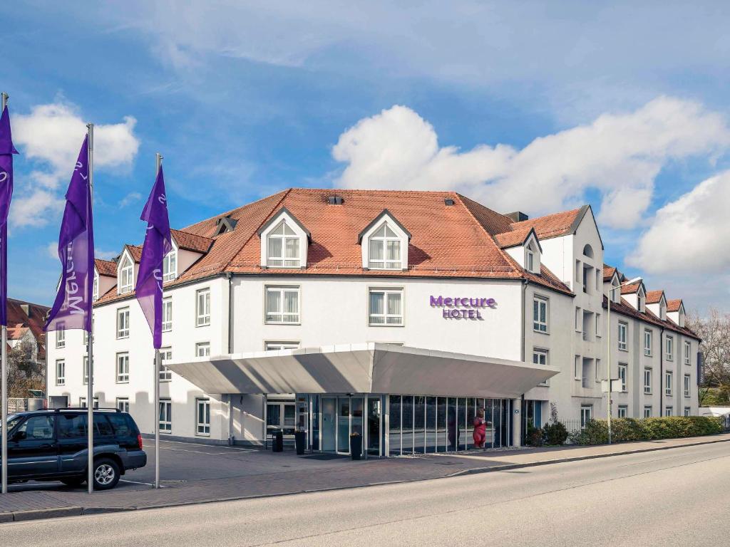 a large white building with purple flags in front of it at Mercure Hotel München Airport Freising in Freising