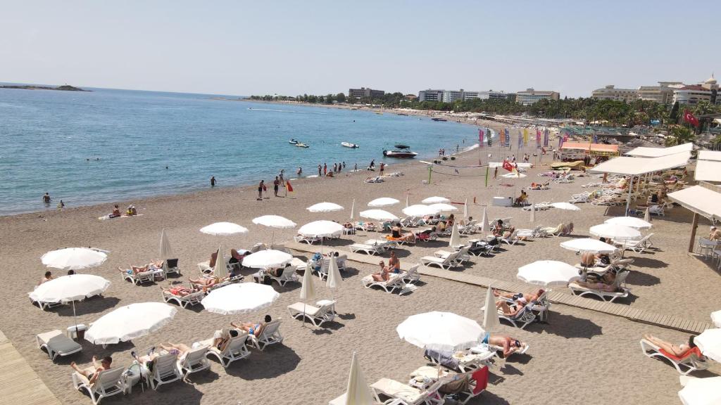 a beach with umbrellas and a crowd of people at Lofts Alanya Lina in Okurcalar
