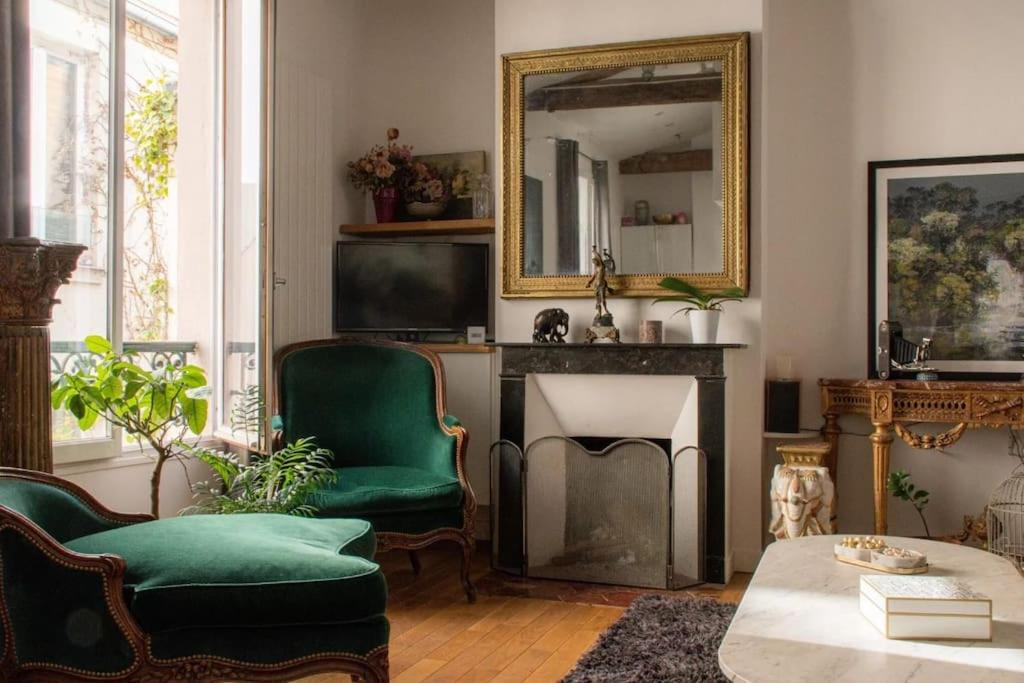 ein Wohnzimmer mit grünen Stühlen und einem Spiegel in der Unterkunft Appartement type loft - 40m² Marais in Paris