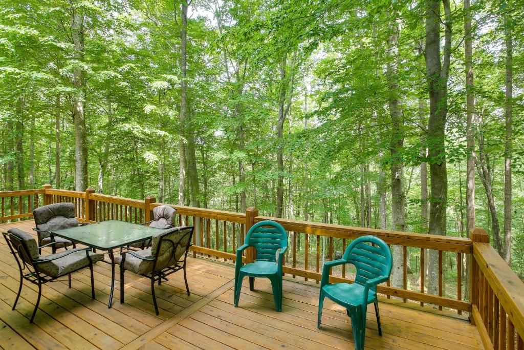 a table and chairs on a deck with trees at Byrdstown Cabin - with Fire Pit, Near Marina and Lake! in Frogue