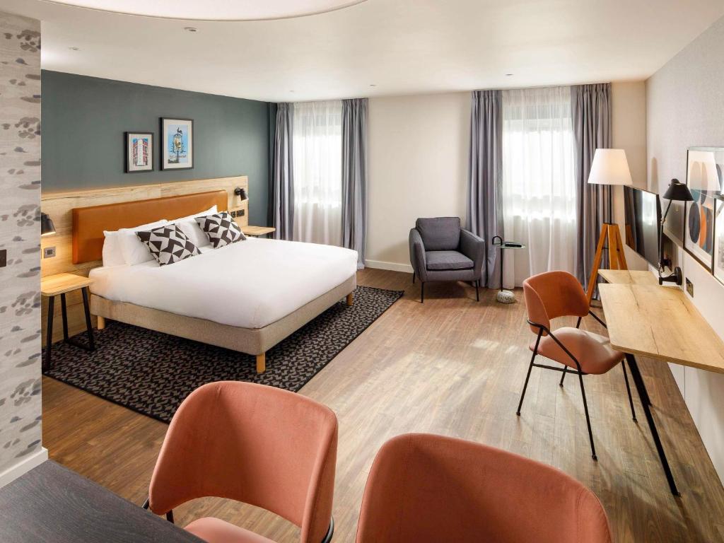 a hotel room with a bed and a desk and chairs at Aparthotel Adagio London Sutton Point in Sutton