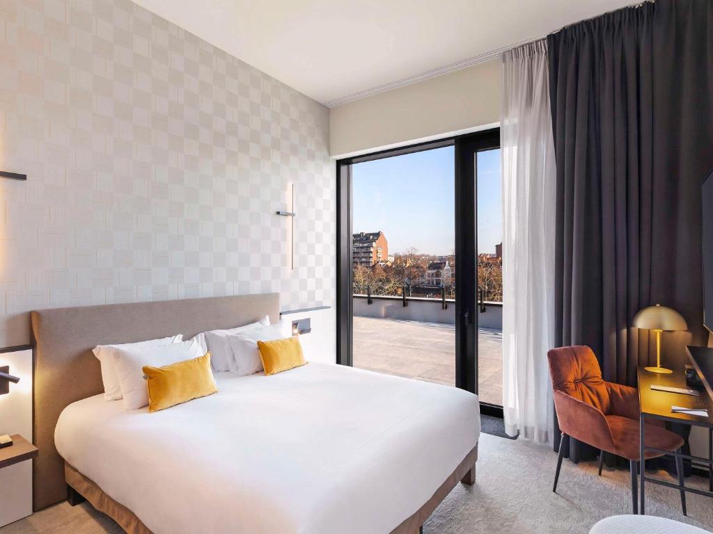 a hotel room with a bed and a large window at Mercure Namur Hotel in Namur