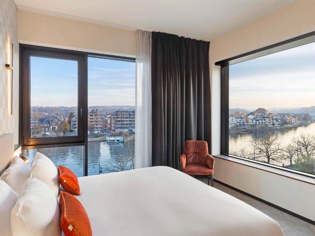 a hotel room with a large bed and large windows at Mercure Namur Hotel in Namur