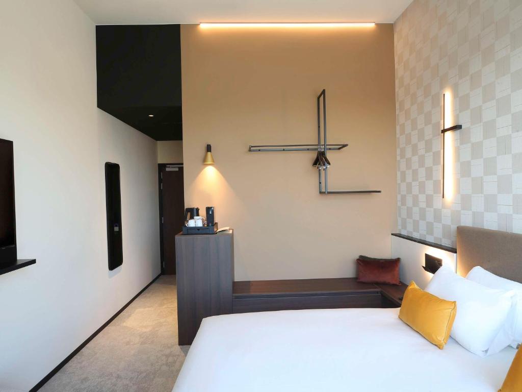 a bedroom with a large white bed with yellow pillows at Mercure Namur Hotel in Namur
