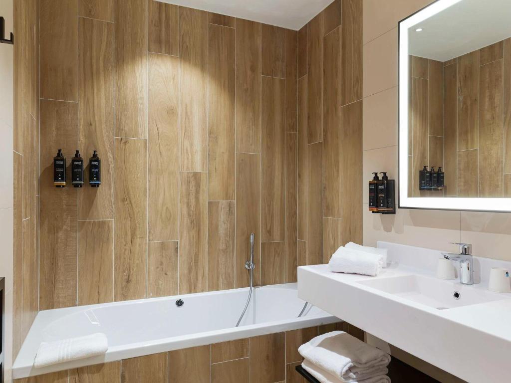 a bathroom with a tub and a sink and a mirror at Mercure Namur Hotel in Namur